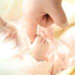 baby gripping mother's finger