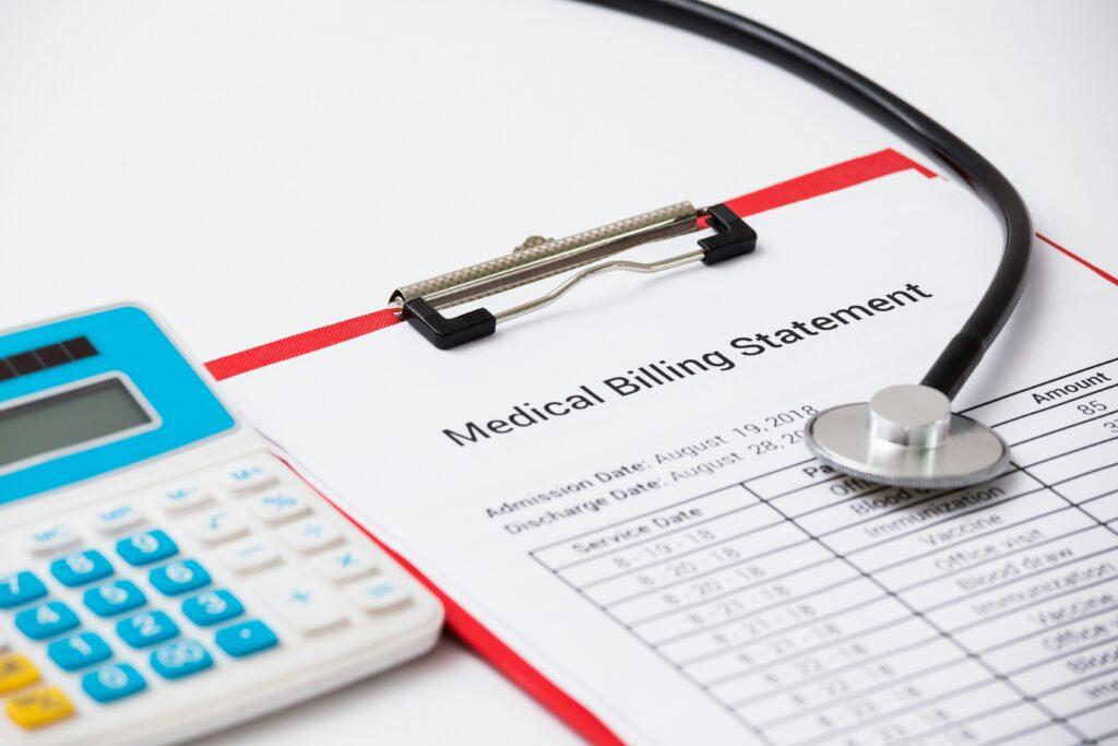 A close-up of a medical billing statement on a red clipboard, accompanied by a stethoscope and a calculator, representing healthcare costs and financial documentation.